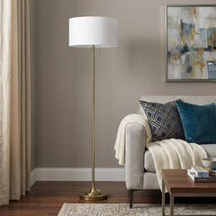 64" Brass Two Light Traditional Floor Lamp with a white rectangular shade, set in a cozy living room with a sofa and artwork.