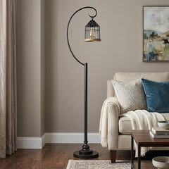 63" Bronze Traditional Shaped Floor Lamp with a curved arm and cage-style shade, placed beside a cozy sofa in a living room.