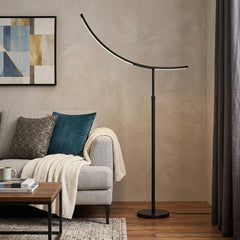 74" Bronze Adjustable LED Traditional Shaped Floor Lamp with a curved design, placed beside a cozy sofa and decorative throw.