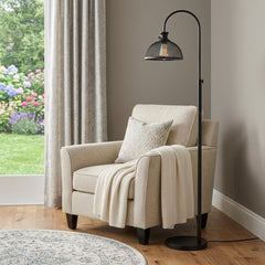 61" black adjustable floor lamp with a bronze dome shade beside a cozy chair and a decorative throw in a bright room.