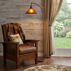 65" rusted traditional floor lamp with a rust empire shade, beside a cozy armchair and window with a garden view.