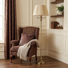 60" Bronze Four Light Traditional Floor Lamp with Beige Square Shade beside a cozy armchair and decorative shelves.