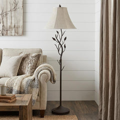 62" grey traditional floor lamp with a brown bell shade, featuring a decorative branch design, placed beside a cozy sofa.