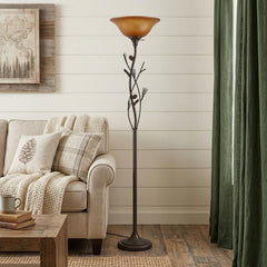 72" Amber Torchiere Floor Lamp with a brown glass dome shade, featuring a decorative branch design, placed beside a cozy sofa