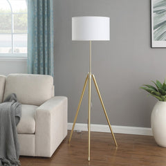 Gold metal adjustable tripod floor lamp with a white linen drum shade, set beside a light-colored sofa in a modern living roo