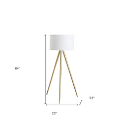 Gold metal adjustable tripod floor lamp with a white linen drum shade, measuring 64 inches tall and 23 inches wide.