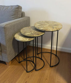 Set of three nested tables with natural wood tops and black iron frames, featuring a round design and geometric pattern.
