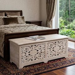 52" White Distressed Solid Wood Carved Floral Storage Ottoman with intricate floral design, placed in a stylish bedroom setti