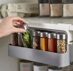 User placing spice jar into wall-mounted organizer, emphasizing practical kitchen organization and accessibility.